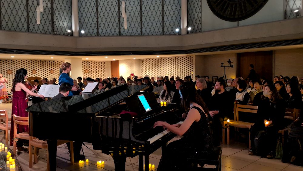 A candlelit concert with a pianist and violinist performing for a seated audience